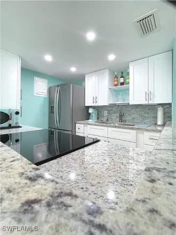 a large kitchen with kitchen island granite countertop a sink and white cabinets