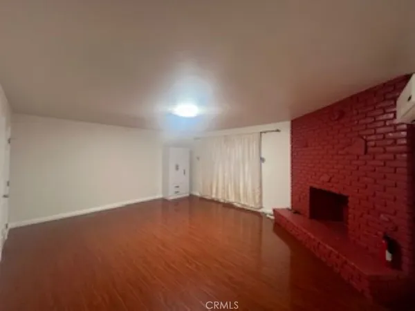 a view of an empty room with wooden floor and a fireplace