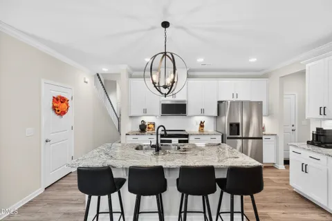 a kitchen with stainless steel appliances granite countertop a stove a sink dishwasher a microwave oven with a dining table and chairs