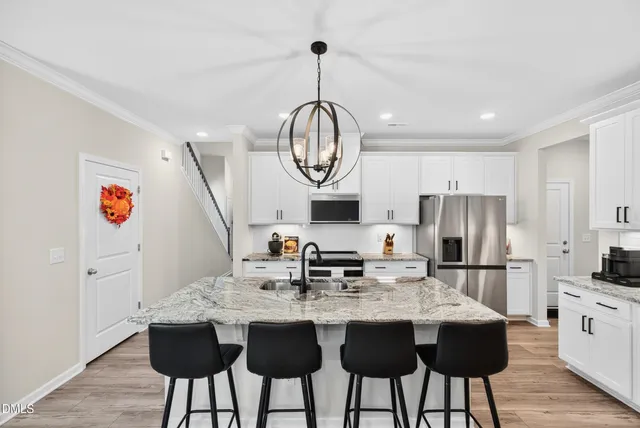 a kitchen with stainless steel appliances granite countertop a stove a sink dishwasher a microwave oven with a dining table and chairs