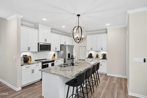 a kitchen with stainless steel appliances a sink dishwasher a stove a refrigerator and a dining table with wooden floor