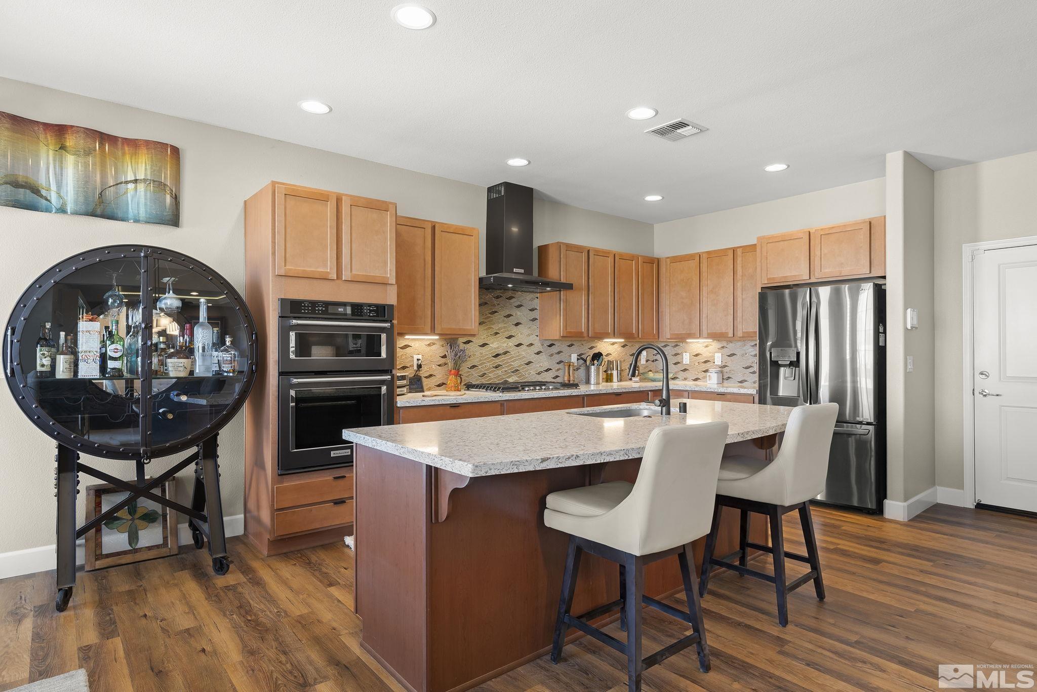 2239 Windflower Drive Reno, NV 89521 - Photo 13 of 40 a kitchen with stainless steel appliances granite countertop a stove a refrigerator a sink dishwasher a dining table and chairs with wooden floor