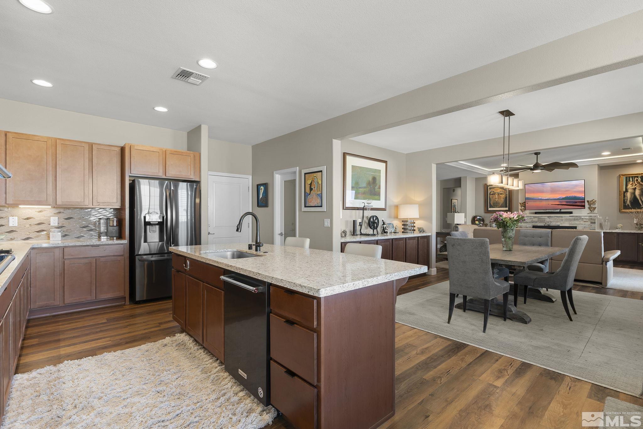 2239 Windflower Drive Reno, NV 89521 - Photo 15 of 40 a large kitchen with stainless steel appliances kitchen island granite countertop a table chairs in it and wooden floors