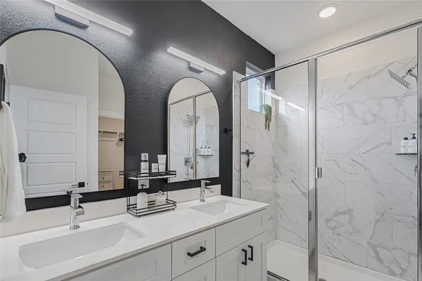 a bathroom with a double vanity sink mirror and shower