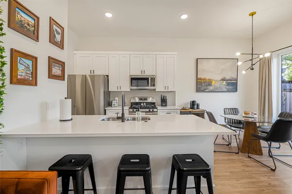 a living room with furniture a chandelier and kitchen view