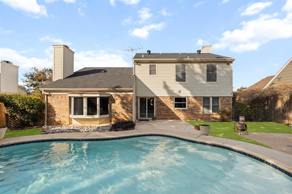 a white house with a yard and table and chairs under an umbrella