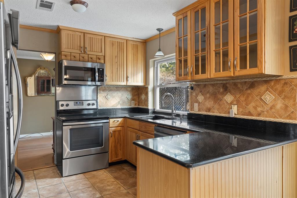 3708 Windsong Lane Bedford, TX 76021 - Photo 4 of 29 a kitchen with granite countertop a sink stainless steel appliances and cabinets