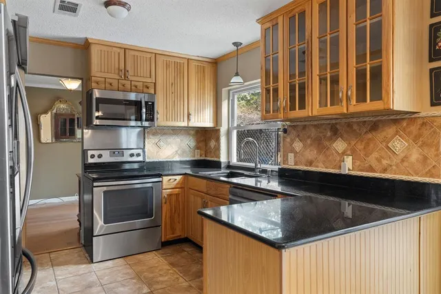 a kitchen with stainless steel appliances granite countertop a refrigerator and a stove top oven