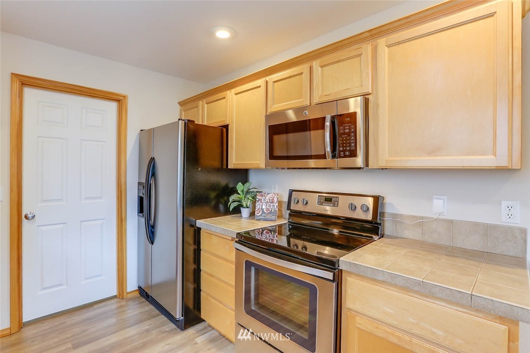 6731 Southeast 3rd Street Renton, WA 98059 - Photo 13 of 31 a kitchen with stainless steel appliances granite countertop white cabinets a refrigerator and a stove top oven