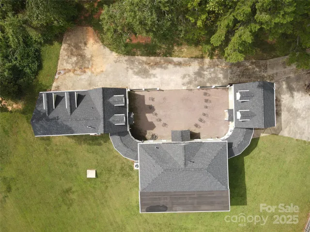 an aerial view of a house with a yard and large trees