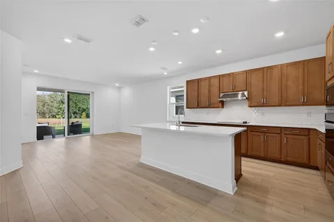 a kitchen with stainless steel appliances granite countertop a refrigerator a sink dishwasher and wooden cabinets with wooden floor