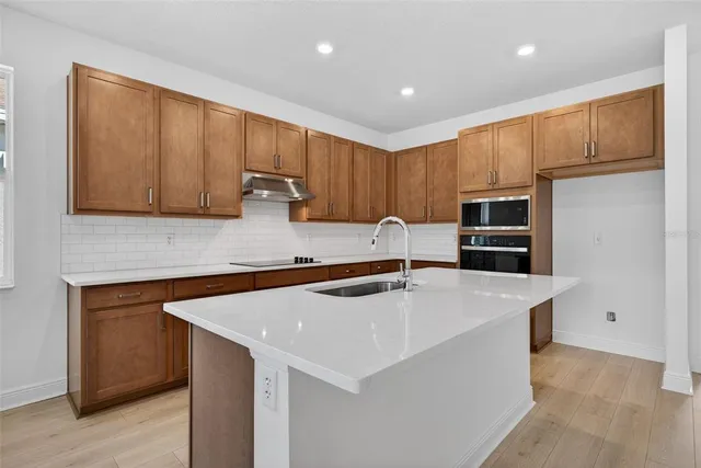 a kitchen with stainless steel appliances a stove a microwave a sink and cabinets