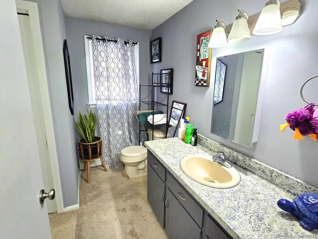 a bathroom with a granite countertop sink a toilet and a mirror
