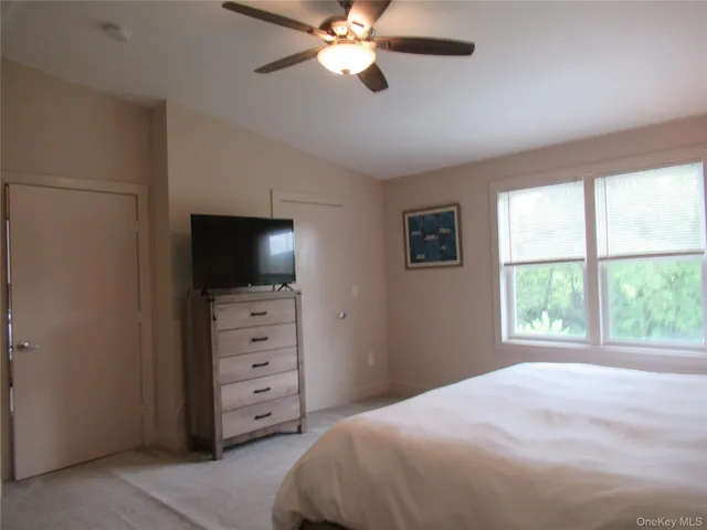 a bedroom with a bed and a flat tv screen on the dresser