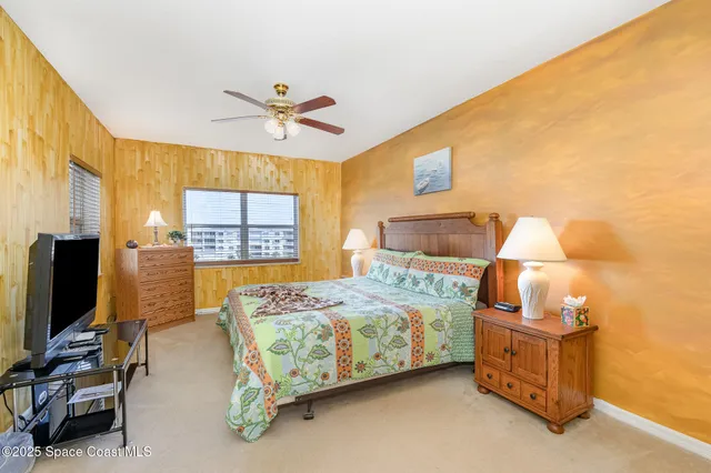 a bedroom with a bed and a flat tv screen on dresser