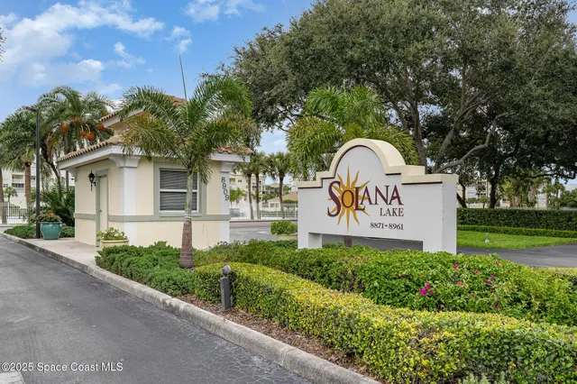 a view of a park that has a sign board large trees