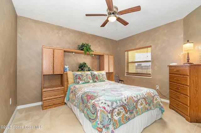 a bedroom with a bed a dresser and a chandelier
