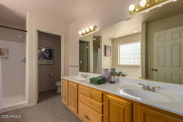 a spacious bathroom with double vanity a mirror and shower