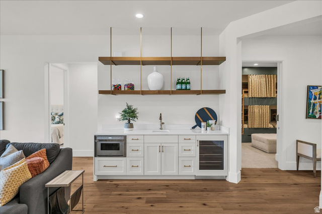 2608 Canyon Ridge Drive St. George, UT 84770 - Photo 59 of 86 Built-in beverage station featuring white cabinetry, a quartz countertop, integrated microwave, beverage cooler, and open shelving with brass hardware