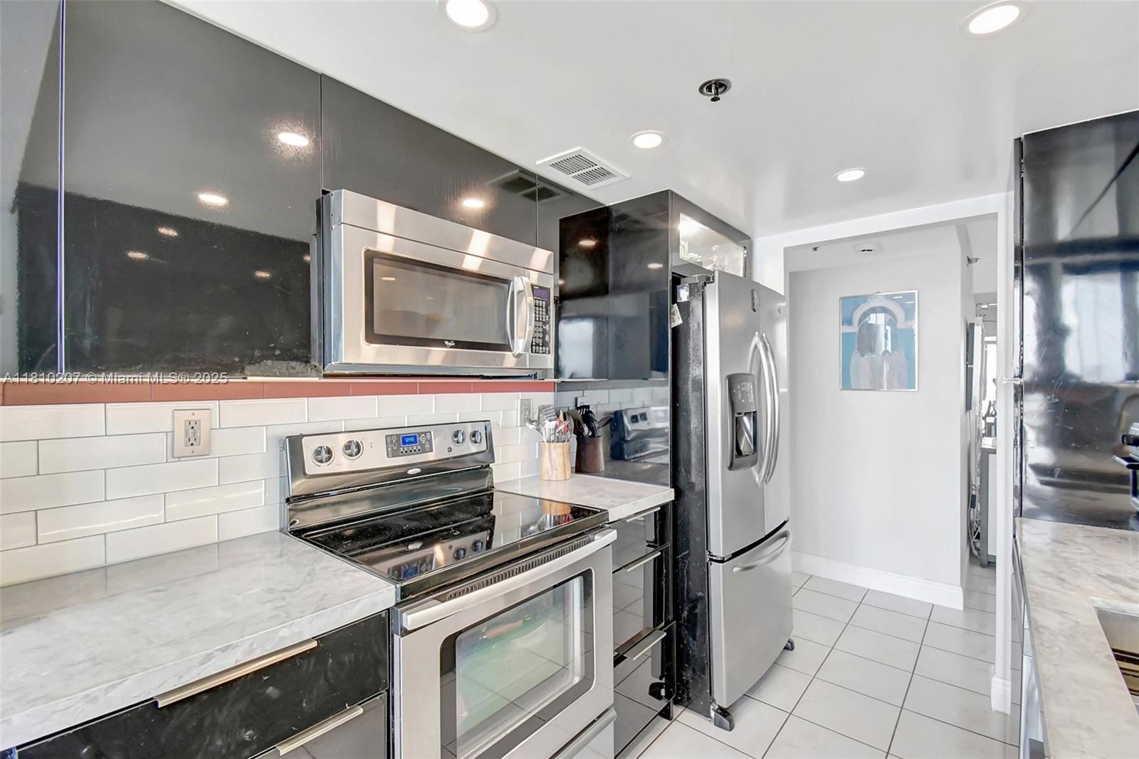 210 174th Street, Unit 2212 Sunny Isles Beach, FL 33160 - Photo 6 of 39 a kitchen with stainless steel appliances granite countertop a refrigerator and a stove top oven