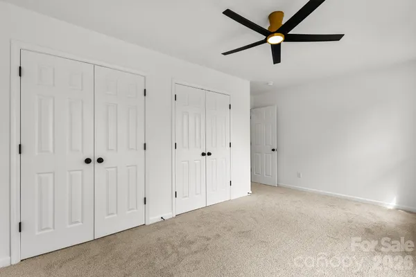 an empty room with windows and ceiling fan