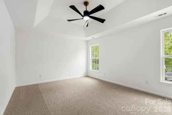 an empty room with windows and ceiling fan
