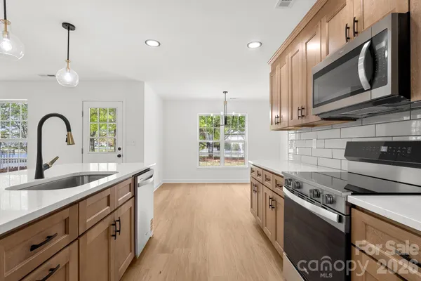 a kitchen with stainless steel appliances granite countertop a sink a stove and a wooden floors