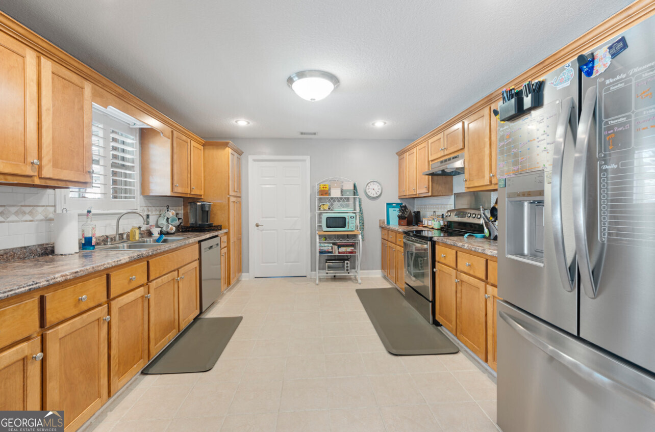 646 Corey Street Baxley, GA 31513 - Photo 15 of 21 a kitchen with stainless steel appliances granite countertop a refrigerator a sink dishwasher a stove and white countertops with wooden floor