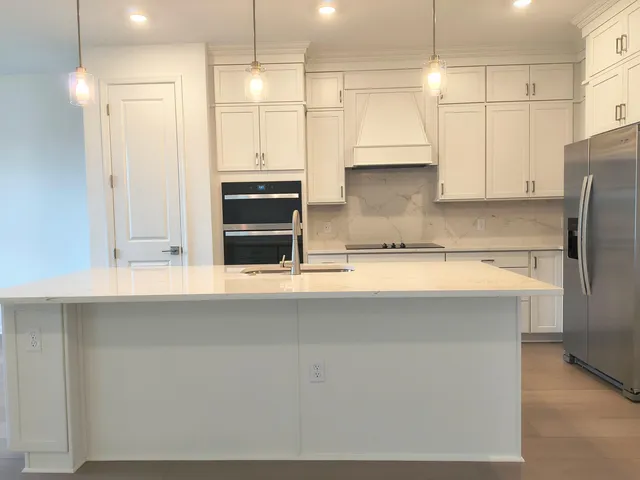 a kitchen with stainless steel appliances a refrigerator a stove and a sink with wooden floor