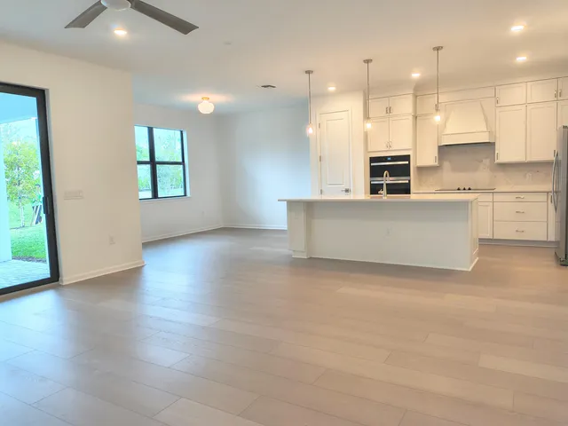 a view of kitchen with kitchen island wooden floors appliances and cabinets