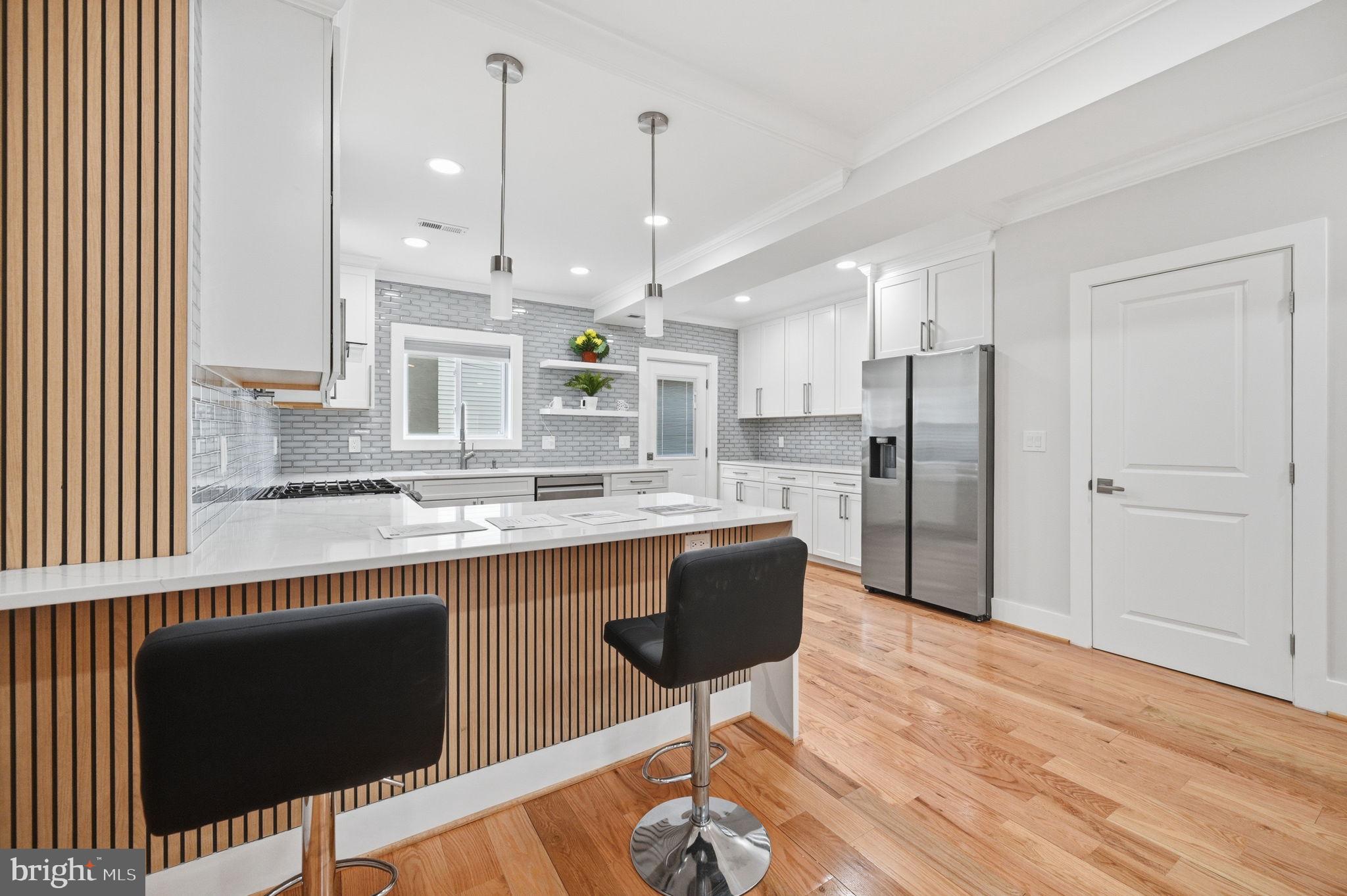 4902 4th Street Northwest Washington, DC 20011 - Photo 6 of 24 a kitchen with stainless steel appliances kitchen island granite countertop a refrigerator a stove a sink dishwasher and white cabinets with wooden floor