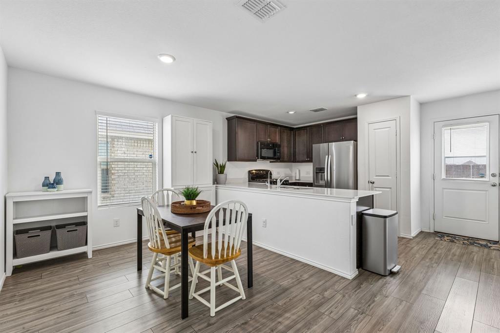3044 Harper Street Little Elm, TX 75068 - Photo 7 of 24 a kitchen with stainless steel appliances kitchen island granite countertop a dining table chairs and granite counter tops