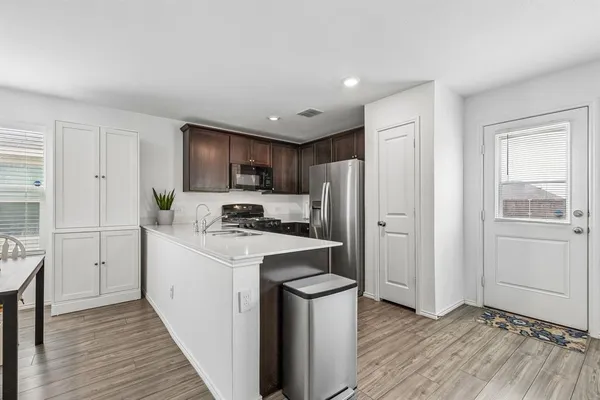a kitchen with a refrigerator a stove top oven and wooden floors