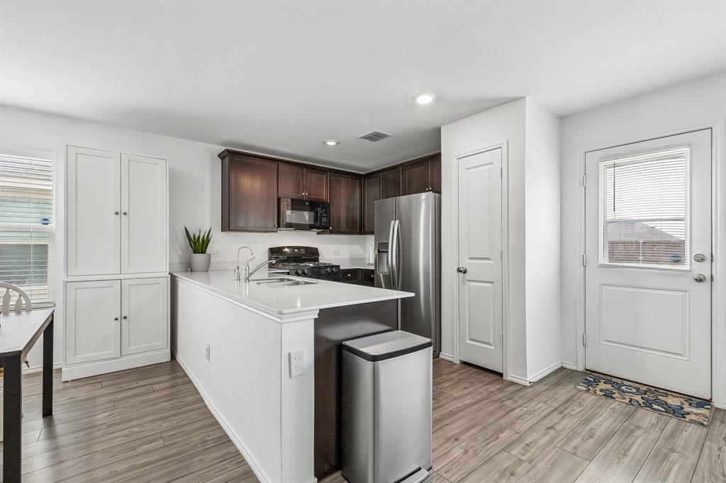 3044 Harper Street Little Elm, TX 75068 - Photo 9 of 24 a kitchen with a refrigerator a stove top oven and wooden floors