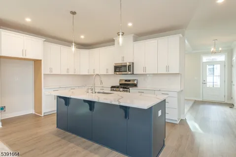 a kitchen with a sink a center island stainless steel appliances and cabinets