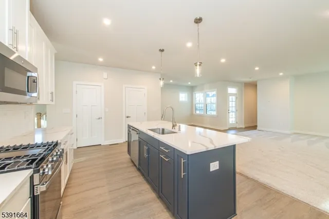 a large kitchen with kitchen island a sink a counter top space and stainless steel appliances