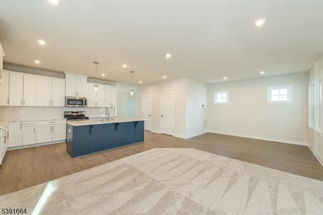 a large kitchen with stainless steel appliances kitchen island a large counter top and a stove top oven