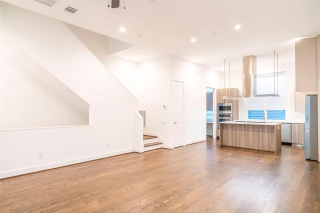 an empty room with wooden floor fan and windows
