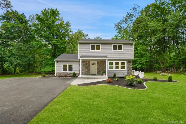 a front view of a house with a garden and tree