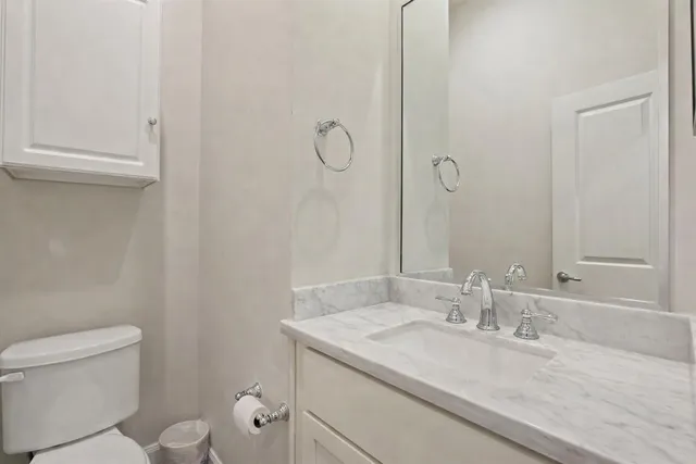a bathroom with a granite countertop sink a toilet and a mirror