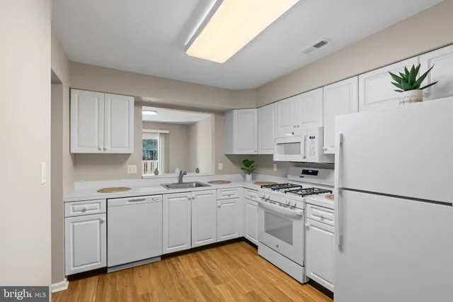 a kitchen with a white cabinets a sink a stove a refrigerator and white cabinets