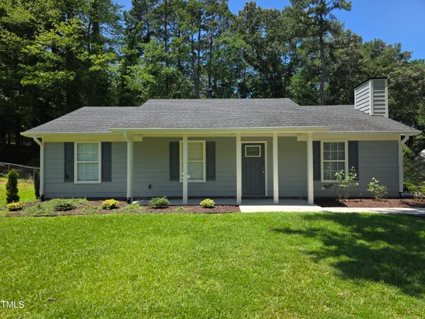 a front view of a house with a garden and trees