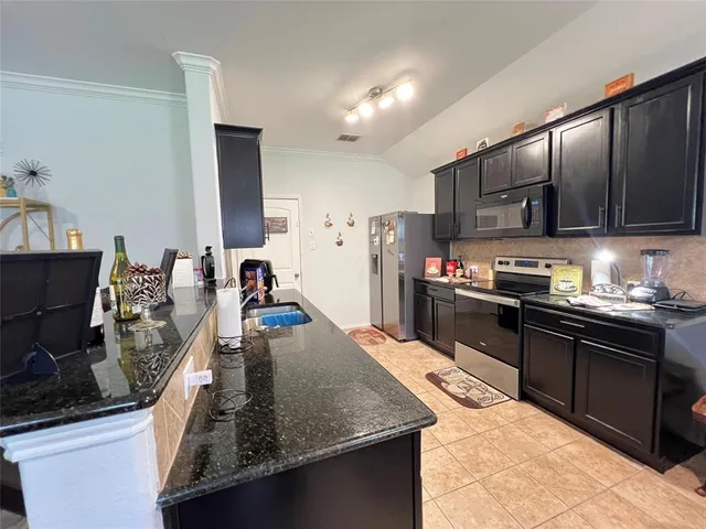 a kitchen with kitchen island granite countertop a sink stove and refrigerator