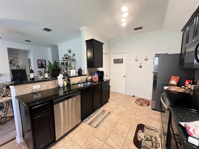 a kitchen with stainless steel appliances kitchen island granite countertop a sink stove and refrigerator