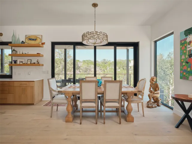 a dining room with furniture large windows and a chandelier