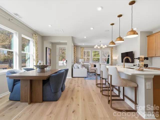 a dining hall with couches a dining table chairs and a kitchen view