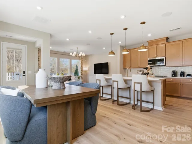 a kitchen with stainless steel appliances kitchen island granite countertop a table chairs sink and cabinets