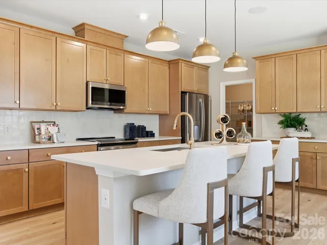 a kitchen with stainless steel appliances a stove a sink a microwave a refrigerator and cabinets