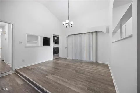 an empty room with wooden floor a fireplace and windows