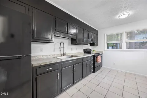 a view of a kitchen with refrigerator and white cabinets